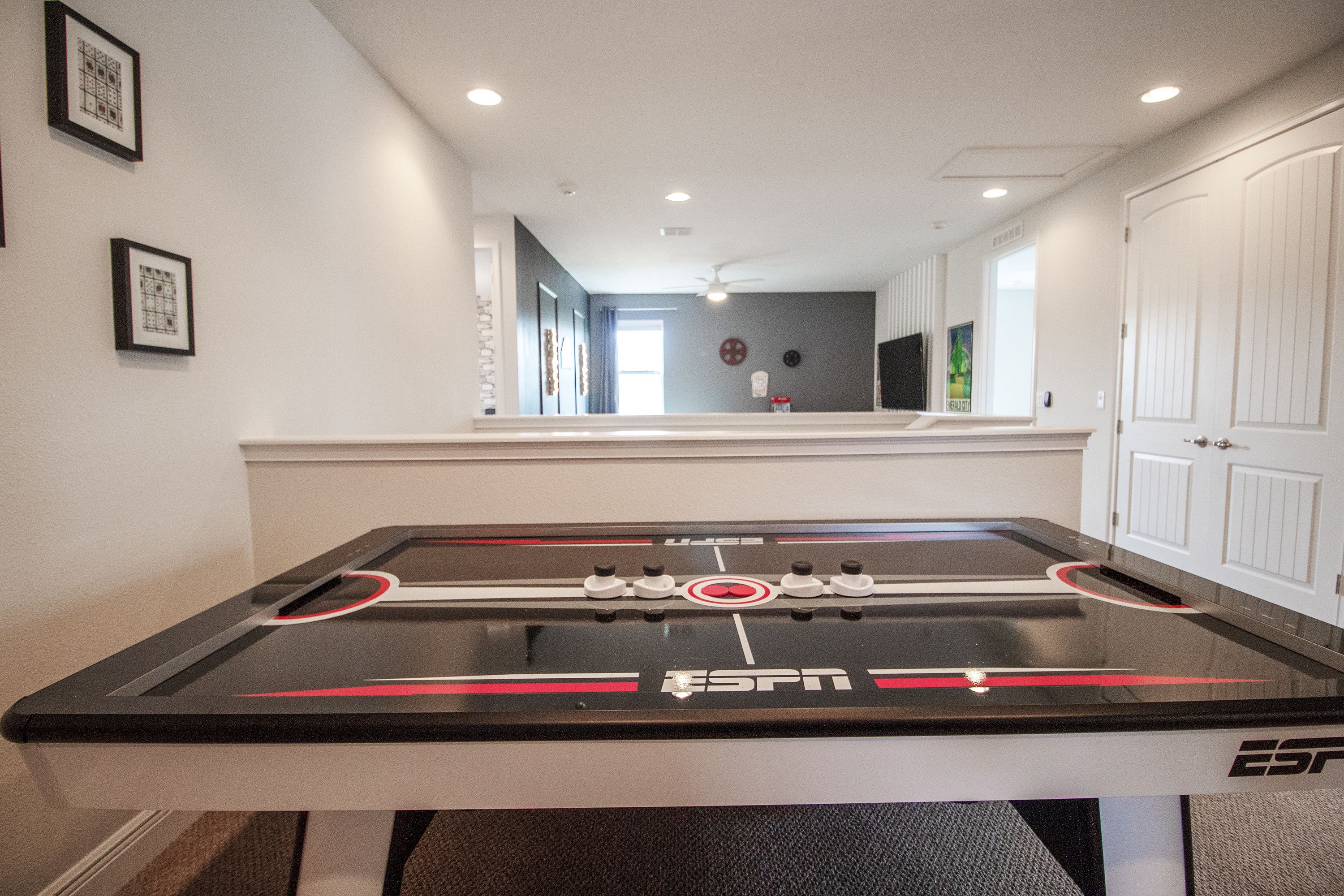A foosball table with the ESPN logo, a white door, and framed pictures on the wall.