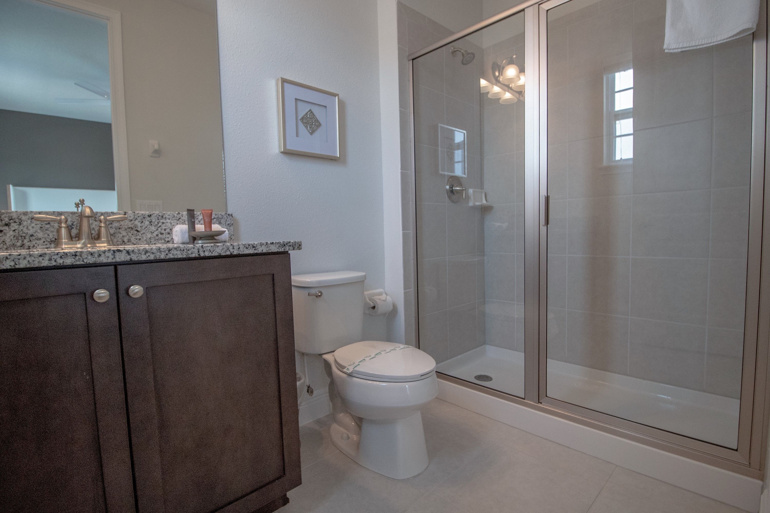 A bathroom with a toilet, a shower with glass doors, and a vanity with a granite countertop.