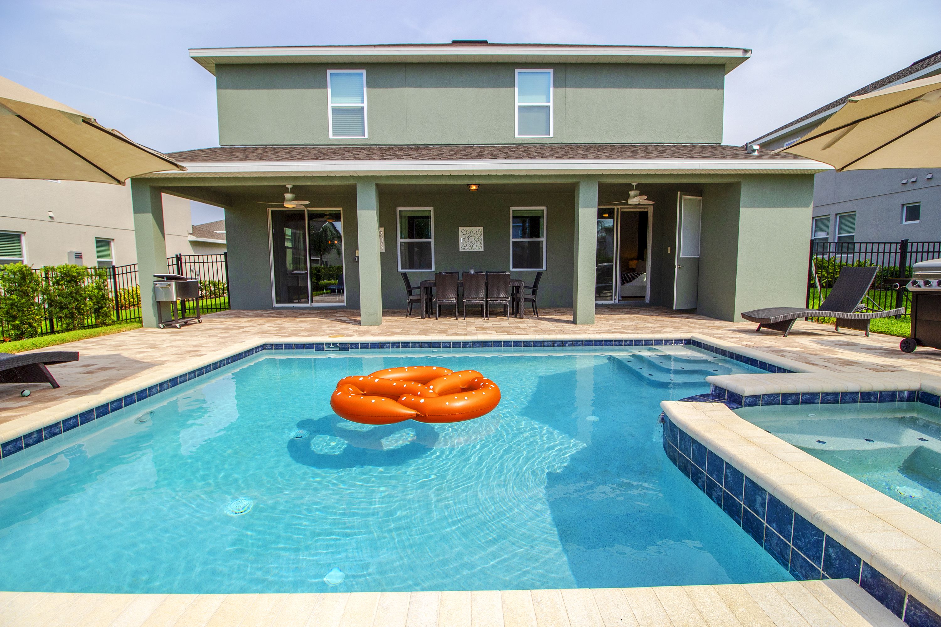 Ein Schwimmbad mit Whirlpool, Sitzgelegenheiten im Freien und einer überdachten Terrasse.
