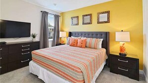 A bedroom with a large bed, two bedside tables, a TV, and a window with curtains. - Encore Resort at Reunion 380 (Kissimmee)
