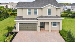 A two-story residential house with a garage, a front lawn, and a driveway. - Encore Resort at Reunion 380 (Kissimmee)