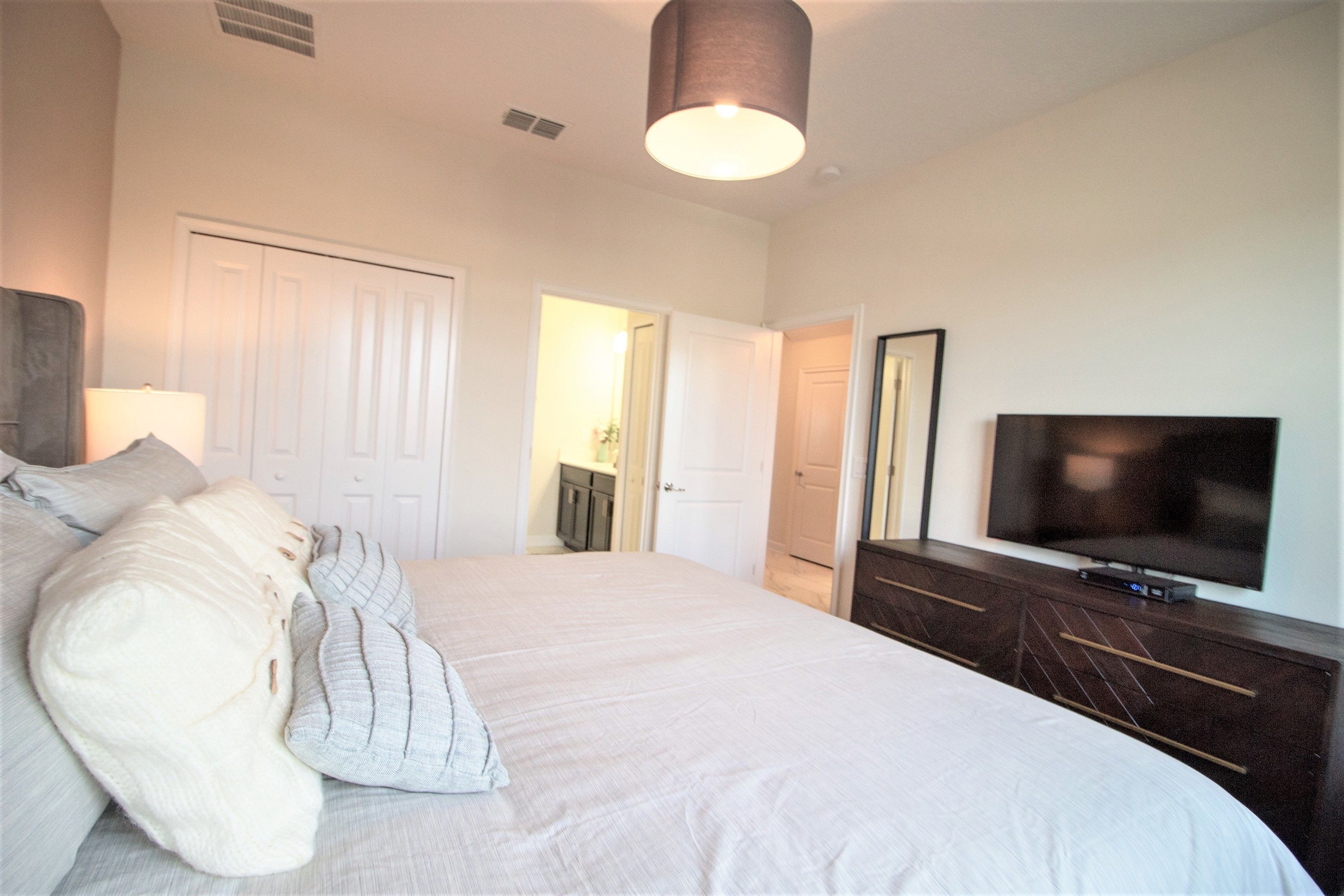 A bedroom with a large bed, a television, and a dresser.