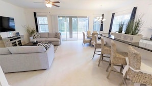 Uma sala de estar moderna com sofá, mesa de centro e área de jantar com cadeiras de vime.