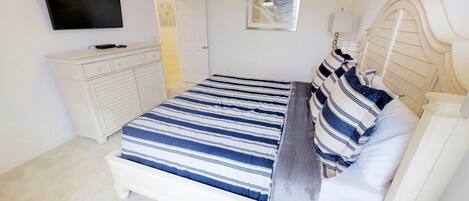 A bedroom with a bed, a dresser, a TV, and artwork on the walls.