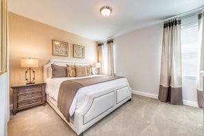 A bedroom with a large bed, two bedside tables, a lamp, and a ceiling light. - Encore Resort at Reunion 7717 (Kissimmee)