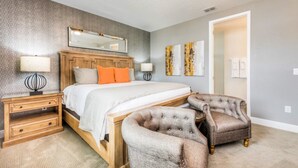 A bedroom with a bed, nightstands, a chair, and artwork on the wall. - Encore Resort at Reunion 7717 (Kissimmee)