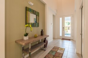 A hallway with a wooden console table, a mirror, and a potted plant. - Sonoma Resort 2692 (Kissimmee)