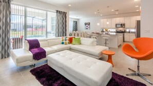 A modern living room with a sectional sofa, a bright kitchen with white cabinets, and a dining area. - Sonoma Resort 2692 (Kissimmee)