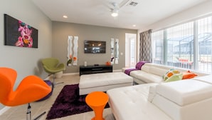 A modern living room with a large window, a flat-screen TV, and contemporary furniture. - Sonoma Resort 2692 (Kissimmee)