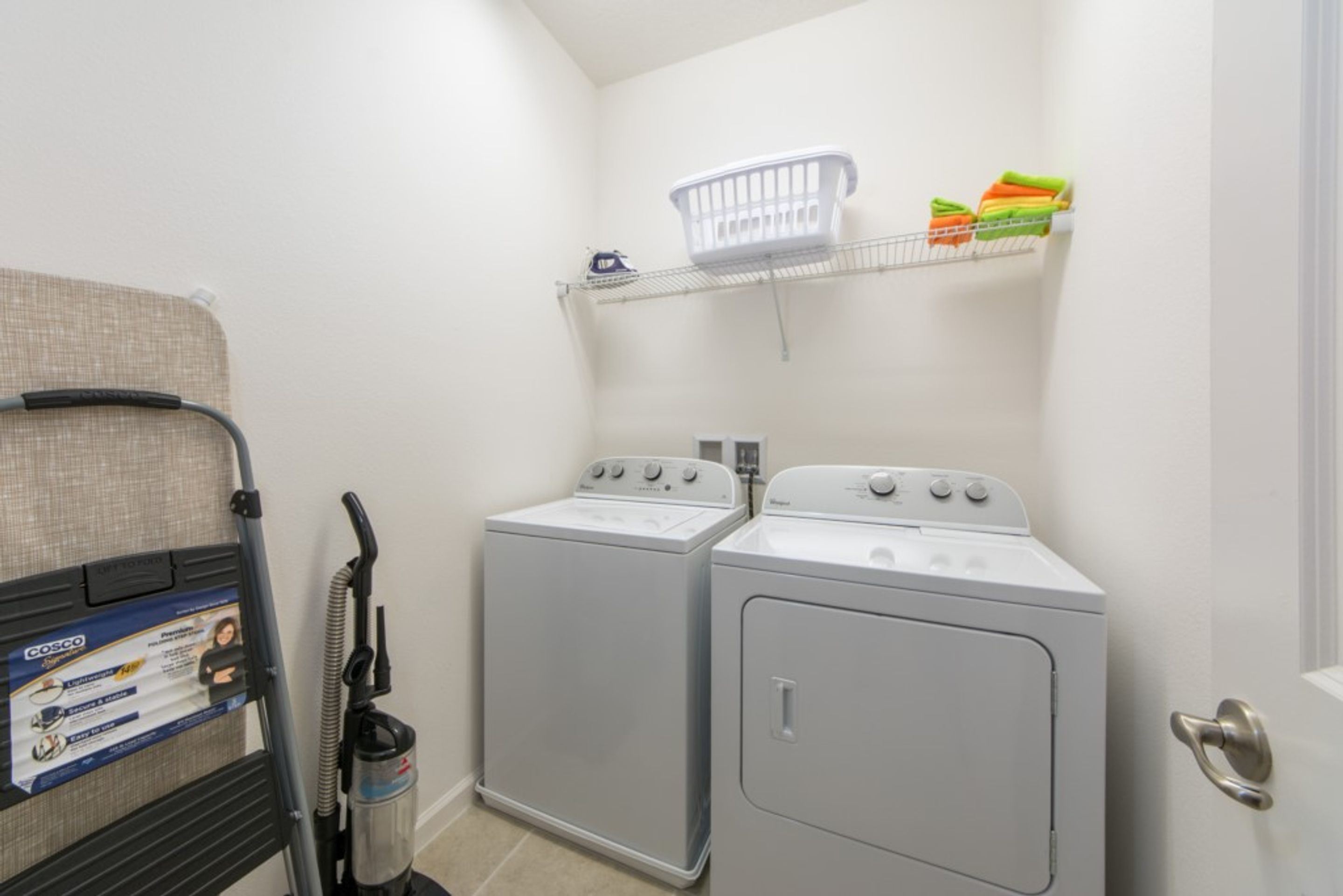 A laundry area with two front-loading washers and a stacked washer and dryer.