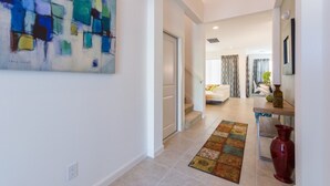 A hallway with a colorful abstract painting, a patterned rug, and a red vase on a table. - Sonoma Resort 2692 (Kissimmee)