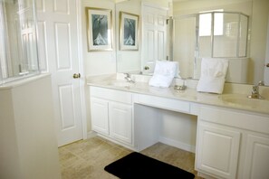 A bathroom with white cabinetry, a large mirror, and two framed pictures on the wall. - Bella Vida 851 (Kissimmee)