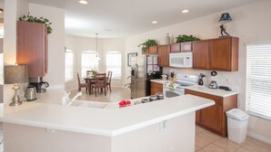 A modern kitchen with a central island, wooden cabinets, and a microwave. - The Shire at West Haven 108 (Davenport)