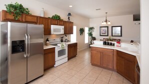 A modern kitchen with wooden cabinets, stainless steel appliances, and a central island. - The Shire at West Haven 108 (Davenport)