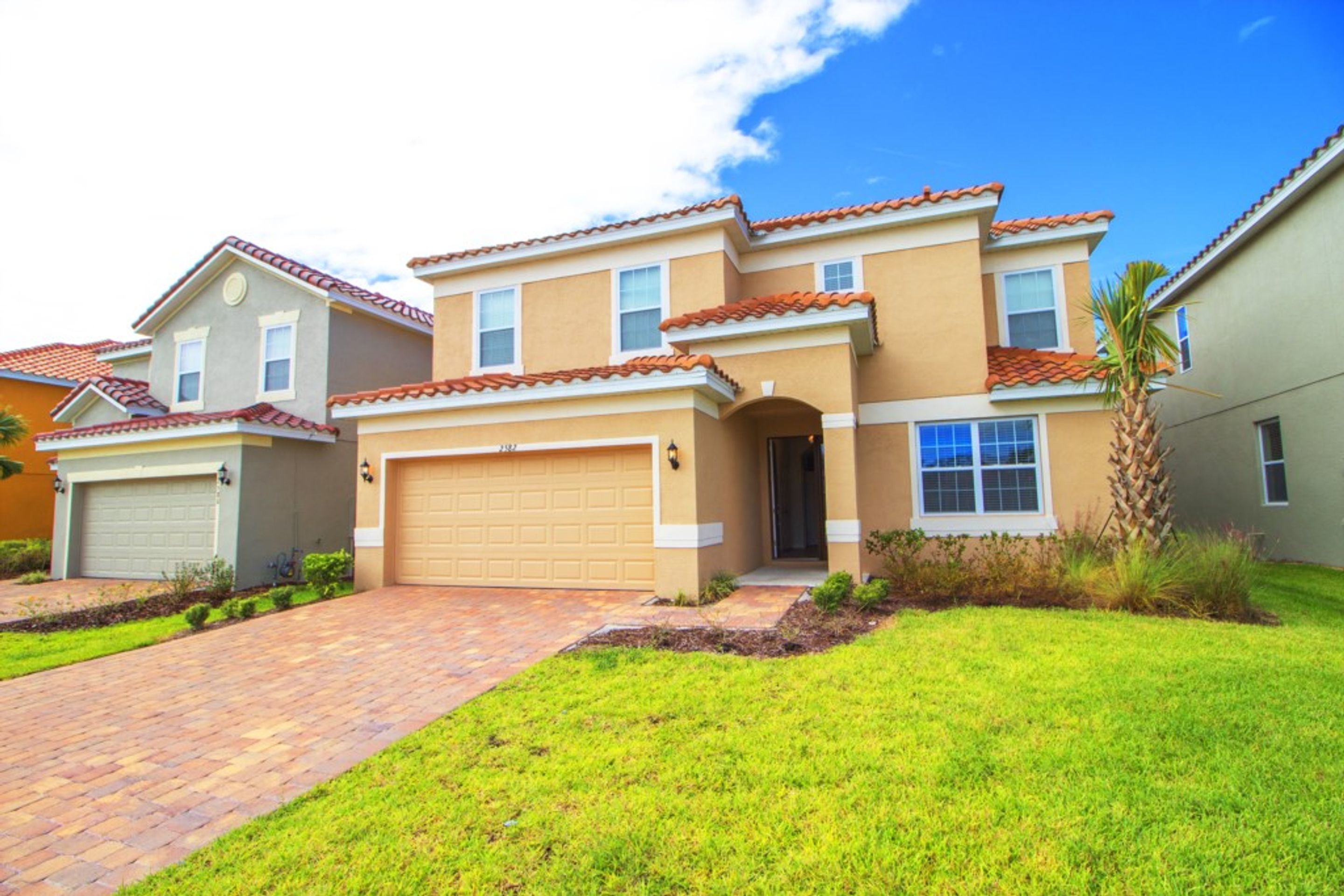 A two-story house with a garage, a driveway, and a well-maintained lawn.