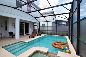 An indoor swimming pool with clear glass walls, lounge chairs, and a floating ring. - Storey Lake 4764 (Kissimmee)