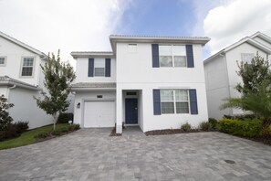 A two-story residential building with a white exterior, blue shutters, and a paved driveway. - Storey Lake 4764 (Kissimmee)