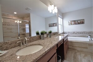 A modern bathroom with a granite countertop, a double sink, a large mirror, and a painting on the wall. - Storey Lake 4764 (Kissimmee)