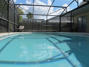 An indoor swimming pool with a clear view of the sky and a wooden fence in the background.
