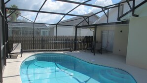 A clear blue pool with a wooden deck, a covered seating area, and a fenced backyard. - Indian Wells 3181 (Kissimmee)
