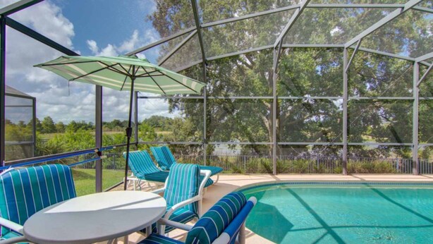 Zona de piscina con área de descanso cubierta, que incluye una mesa y sillas, y una piscina.