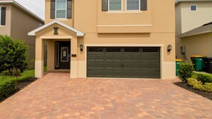 A two-story house with a garage, a front entrance, and a brick driveway. - Encore Resort at Reunion 331 (Kissimmee)