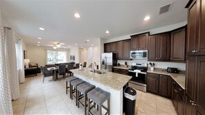 A modern kitchen with dark wood cabinets, stainless steel appliances, and a granite countertop. - Encore Resort at Reunion 331 (Kissimmee)