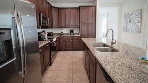 A modern kitchen with granite countertops, stainless steel appliances, and wooden cabinets. - Encore Resort at Reunion 331 (Kissimmee)