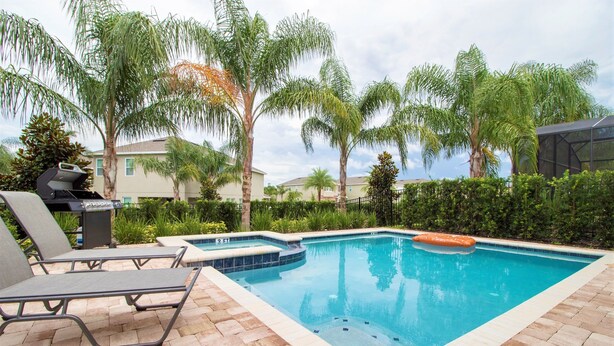 A rectangular swimming pool with a tiled edge, surrounded by a brick patio. There are lounge chairs and a grill area in the foreground. - Encore Resort at Reunion 331 (Kissimmee)