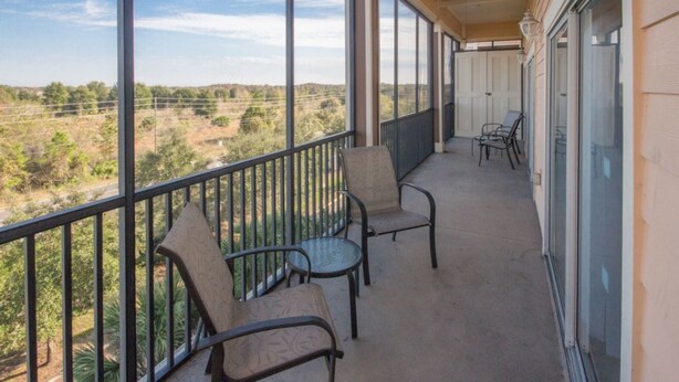 A balcony with a view of a rural landscape, featuring a railing, two chairs, and a table. - Palisades Resort 14200 - 409 (Winter Garden)