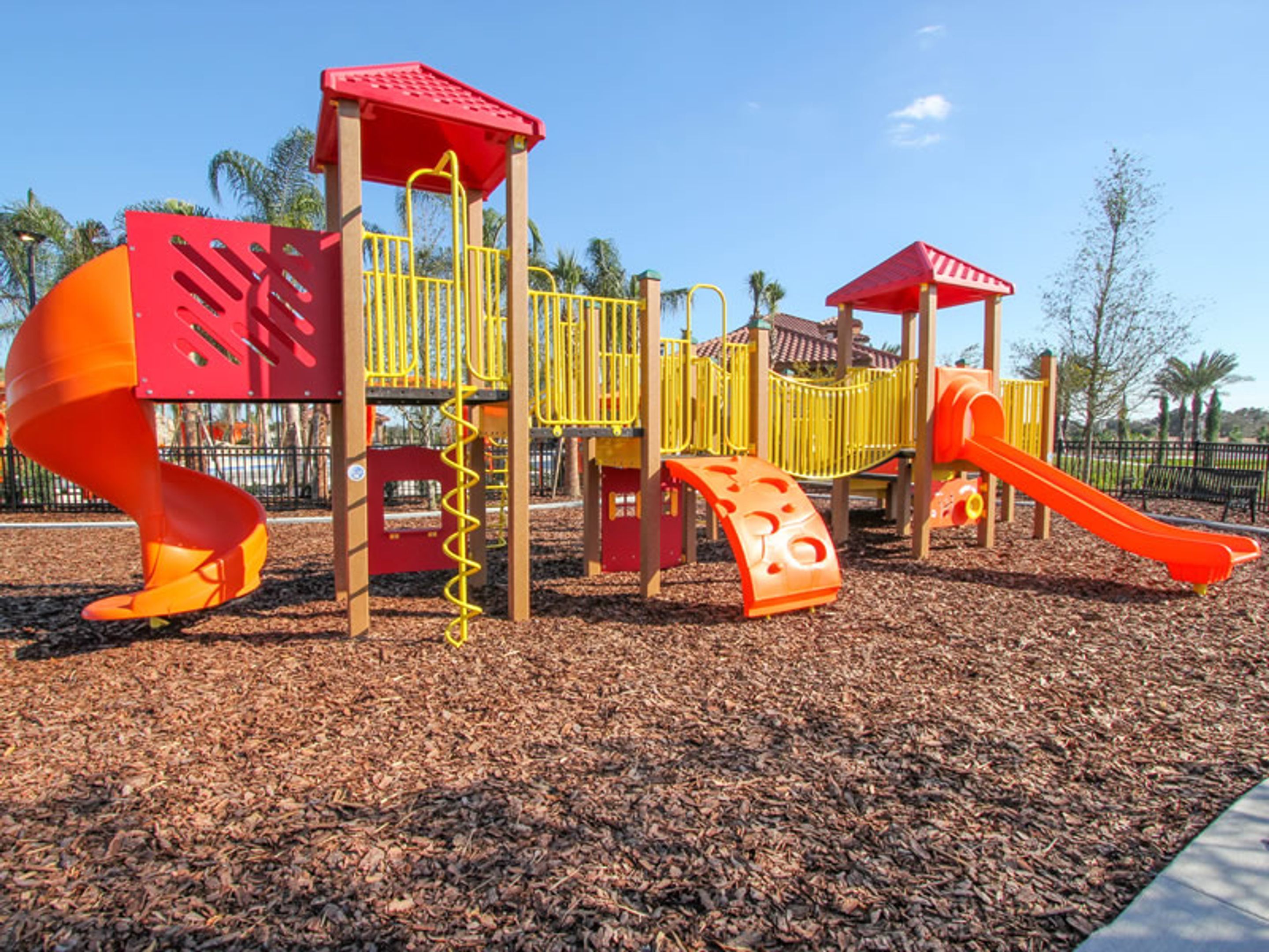 A playground with a spiral slide, climbing structures, and a small bridge.