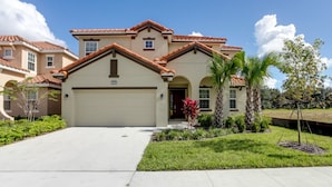 A two-story house with a garage, a well-maintained lawn, and a palm tree.