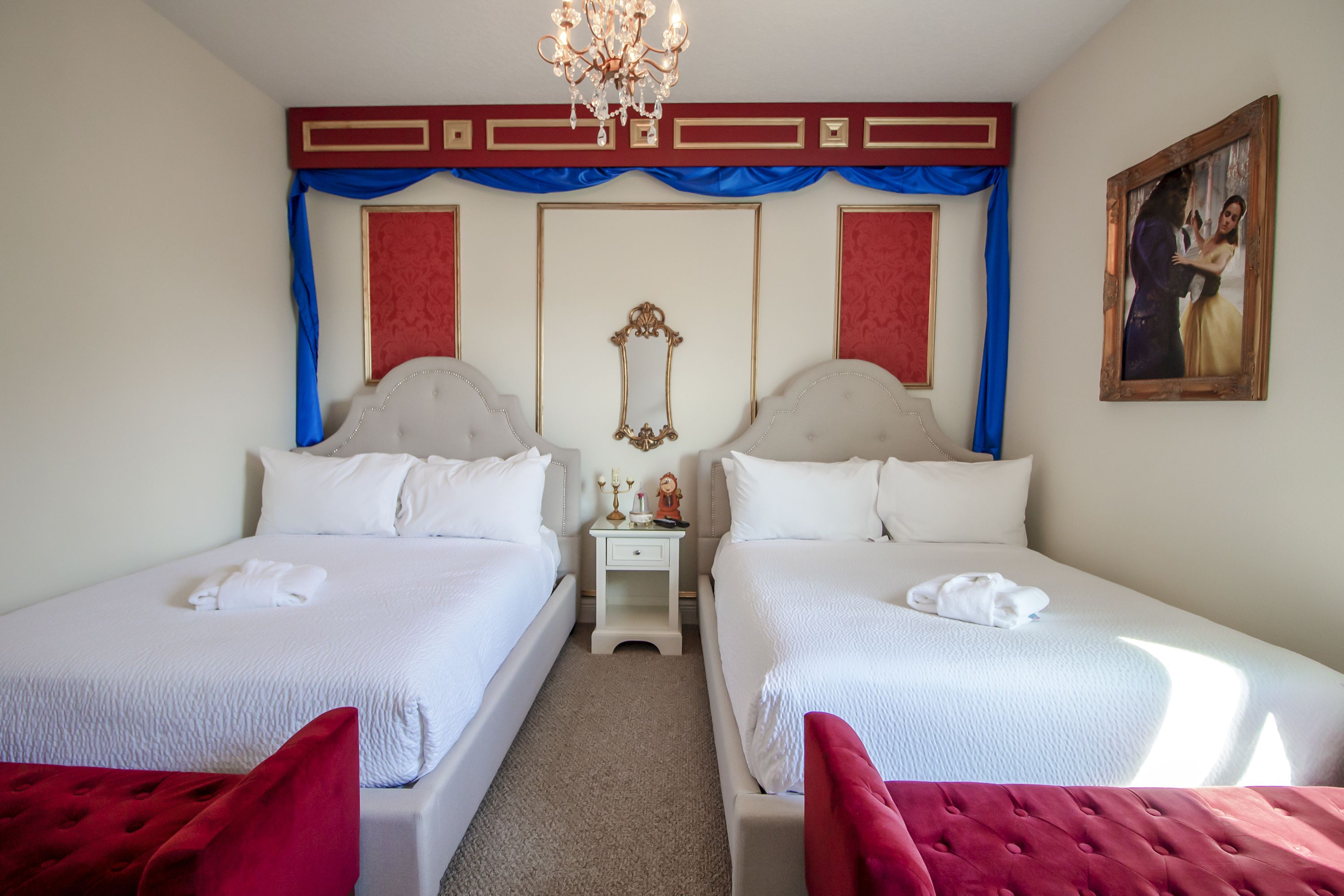 Een hotelkamer met twee bedden, een kroonluchter, een spiegel en een schilderij aan de muur.