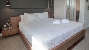 Ein modernes Schlafzimmer mit einem großen Bett, Nachttischen und einem Spiegel.