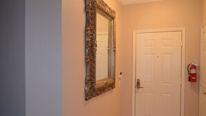 Un pasillo con una puerta blanca y un espejo grande y decorativo en la pared.