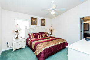 A bedroom with a bed, two bedside tables, a ceiling fan, and a window.