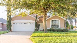 A residential house with a garage, a well-maintained lawn, and a large tree in front. - Indian Creek 8115 (Kissimmee)