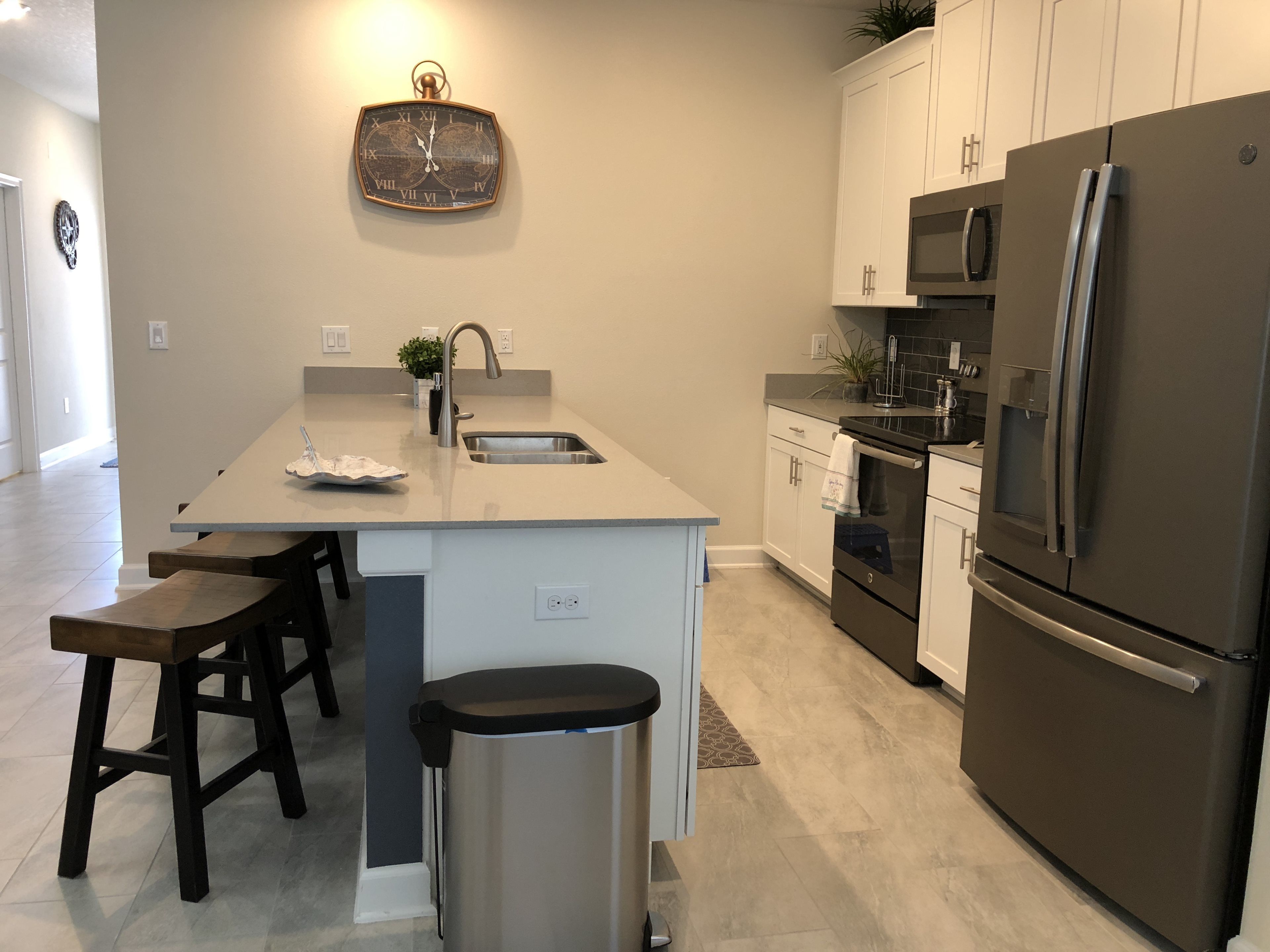 A modern kitchen with a central island, stainless steel appliances, and a world map clock.