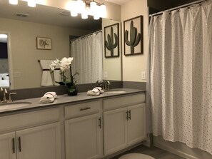 A bathroom with two sinks, a large mirror, and a shower curtain. - Champions Gate 1575 (Davenport)