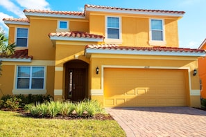 A two-story house with a yellow facade, a brown door, and a yellow garage door. - Golden Palms Vacation Resort 4439 (Kissimmee)