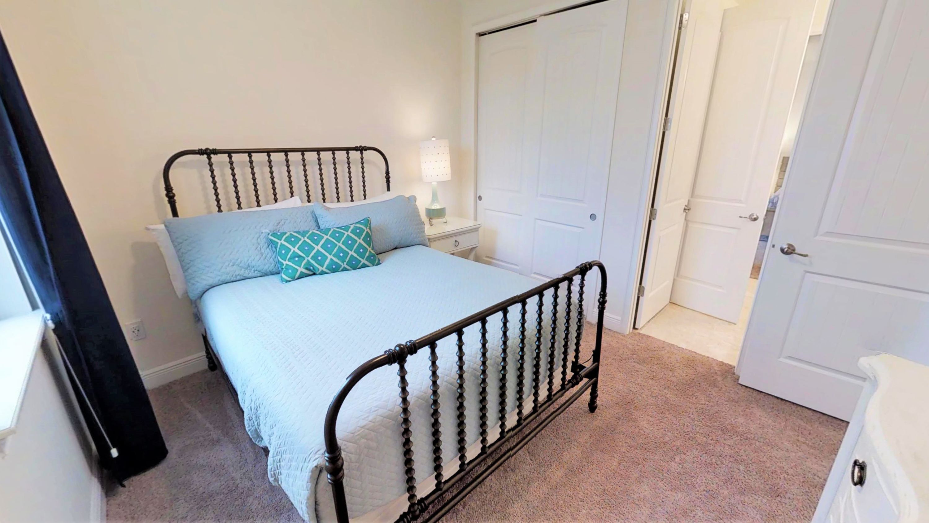 A bedroom with a bed, a nightstand, a lamp, and a wardrobe.