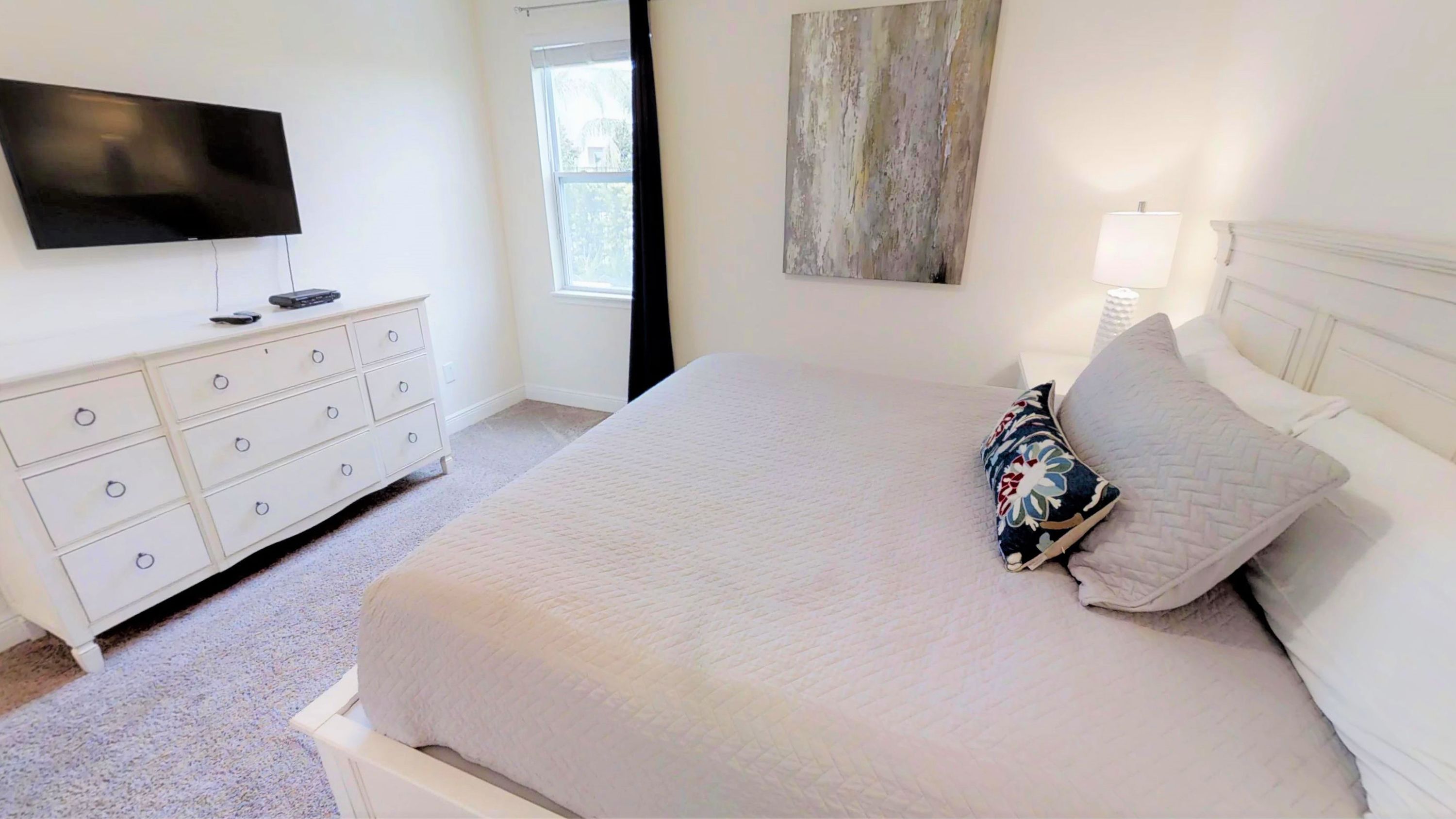 A bedroom with a bed, a dresser, a television, and a window.