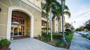A building with a large entrance, a paved walkway, and a parking area with cars. - Vista Cay 4804 B12.403 (Orlando)