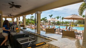 A poolside bar area with a sign reading "Cointreau" and a view of a pool with lounge chairs and umbrellas. - Vista Cay 4804 B12.403 (Orlando)