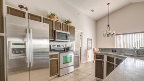 A modern kitchen with stainless steel appliances, a granite countertop, and a large window providing natural light.