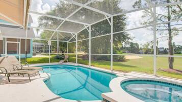 A covered swimming pool with lounge chairs and a view of a golf course.