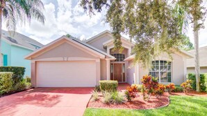 A two-story house with a garage, a front porch, and a landscaped garden.