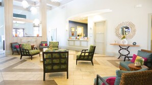 Eine großzügige Lobby mit mehreren Sitzbereichen, darunter Sofas und Sessel, sowie einem Empfangstresen.