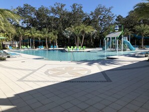 Une piscine dotée de chaises longues, d’un toboggan et de palmiers.