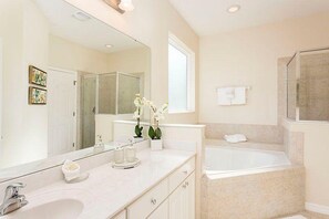 Une salle de bain moderne avec un grand miroir, une baignoire et une douche.